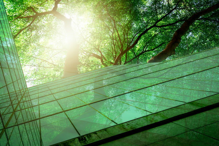 Sustainble green building. Eco-friendly building. Sustainable glass office building with tree for reducing carbon dioxide. Office with green environment. Corporate building reduce CO2. Safety glass